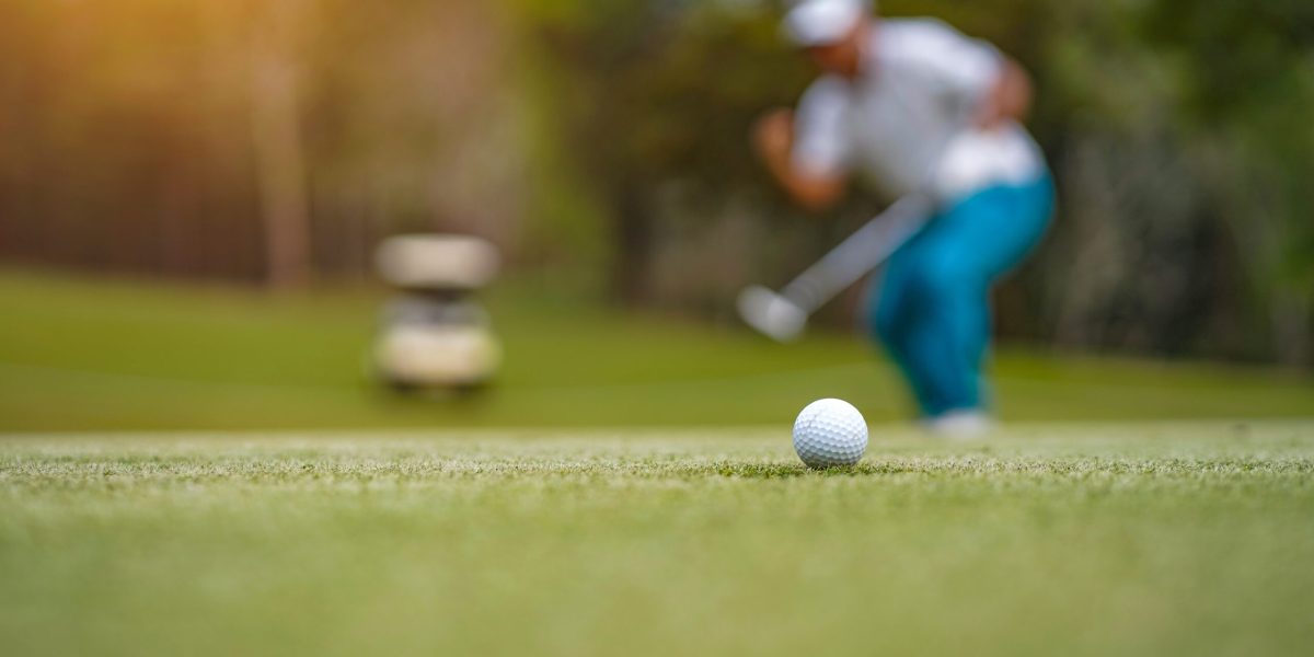Home Golf balls that are going to be hole by golfers at the green grass golf course at sunset.